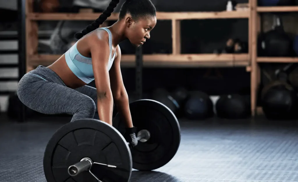 Woman doing weight training at the gym to support bone strength and osteoporosis treatment.